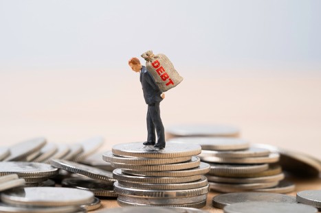 Figur mit Schuldensack auf dem Rücken